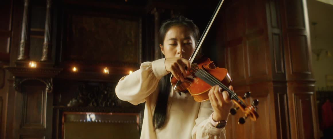 A woman is playing the violin indoors