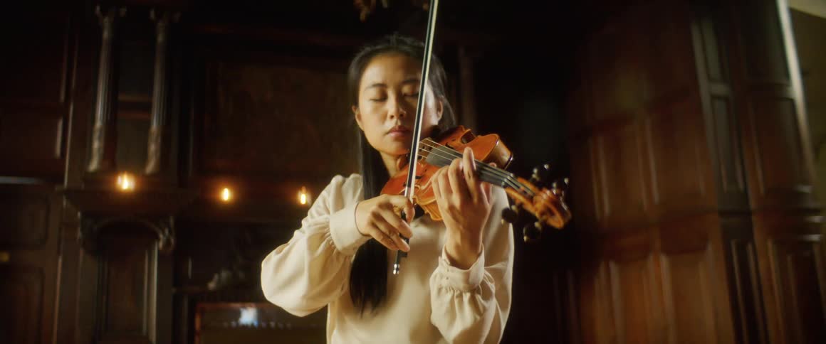 A woman is playing the violin indoors