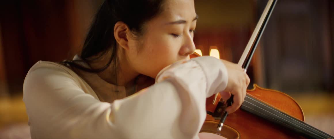 A woman is playing the violin indoors