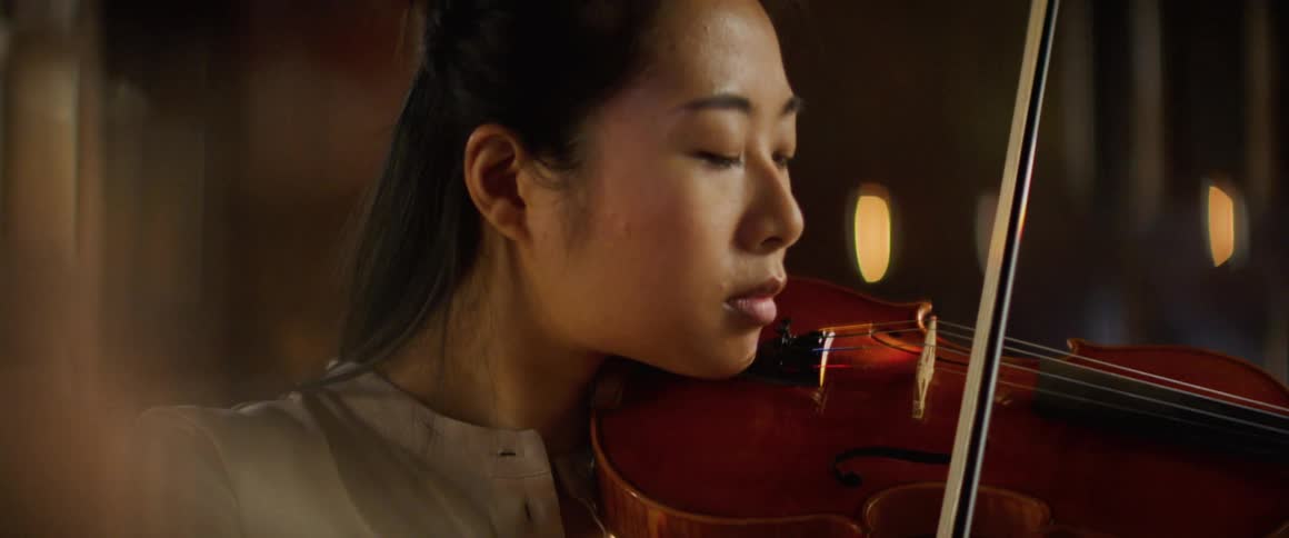 Asian female violinist plays a violin in a large room