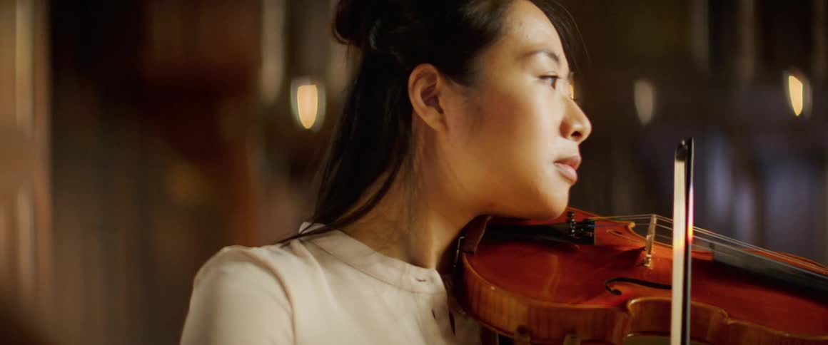 A young woman playing the violin indoors