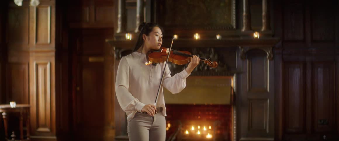 A teenage girl plays the violin at home
