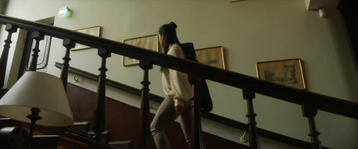 A woman is walking up a flight of stairs in a house