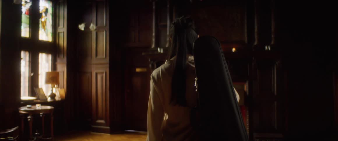 A woman carrying a musical instrument in a case walks through a building