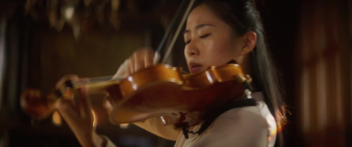 A woman is playing the violin indoors