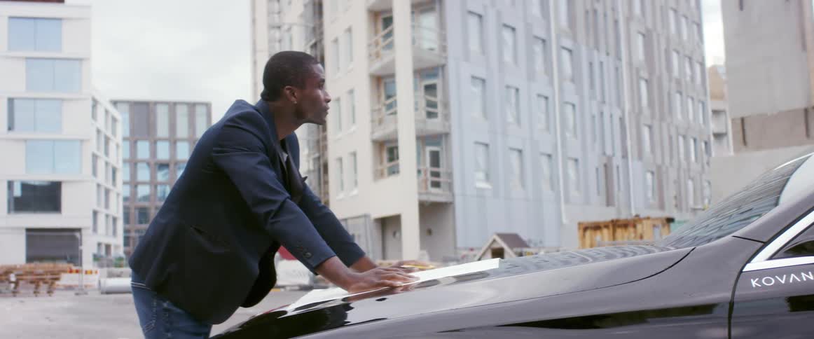 A man is standing outdoors by his car
