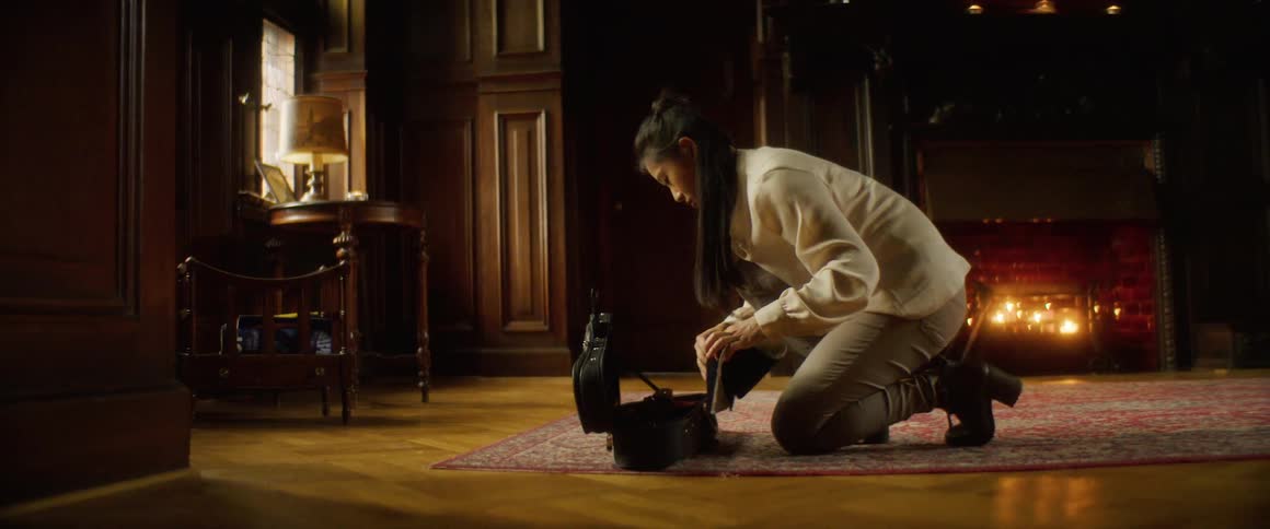 A woman kneels on the ground on a rug to remove her violin from its case