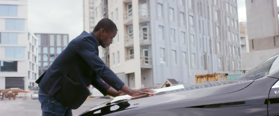 A man is standing by his car in a city