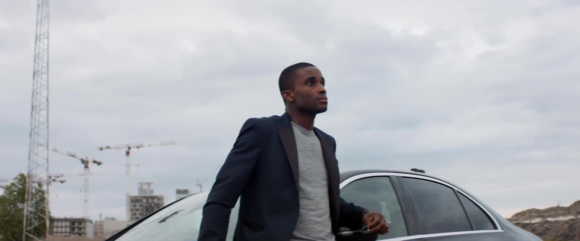 A man is standing by his car outdoors in spring