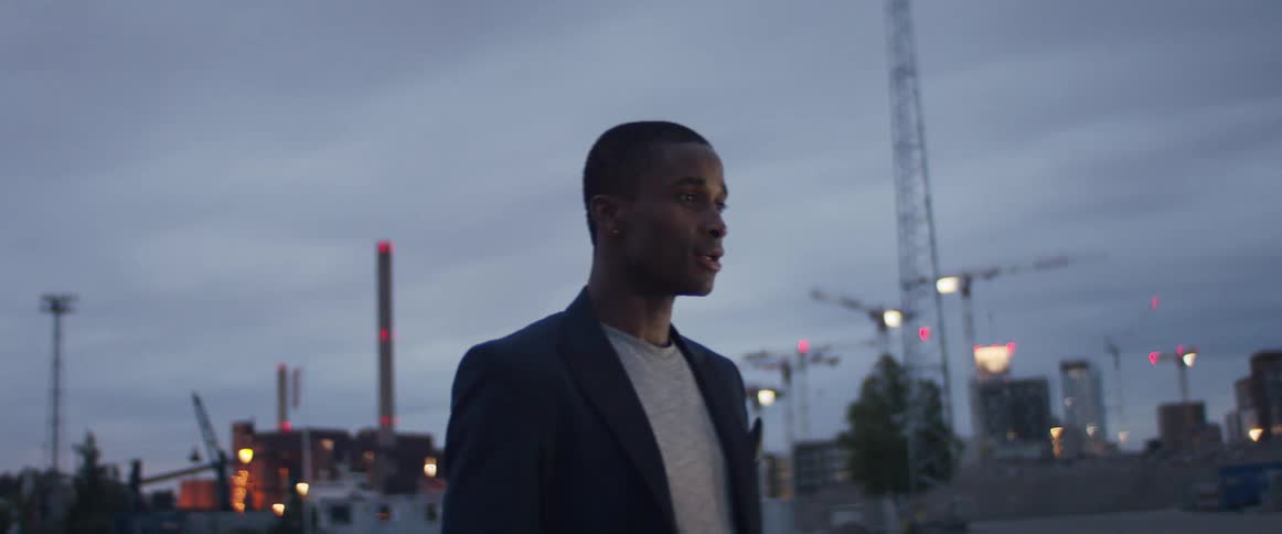 A man is standing in a city at dusk