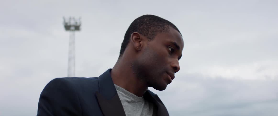 A young black man outside on a cloudy day