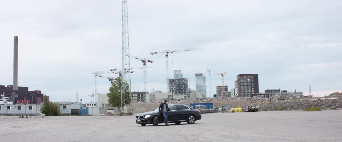 A man leaning against his car in front of a construction site