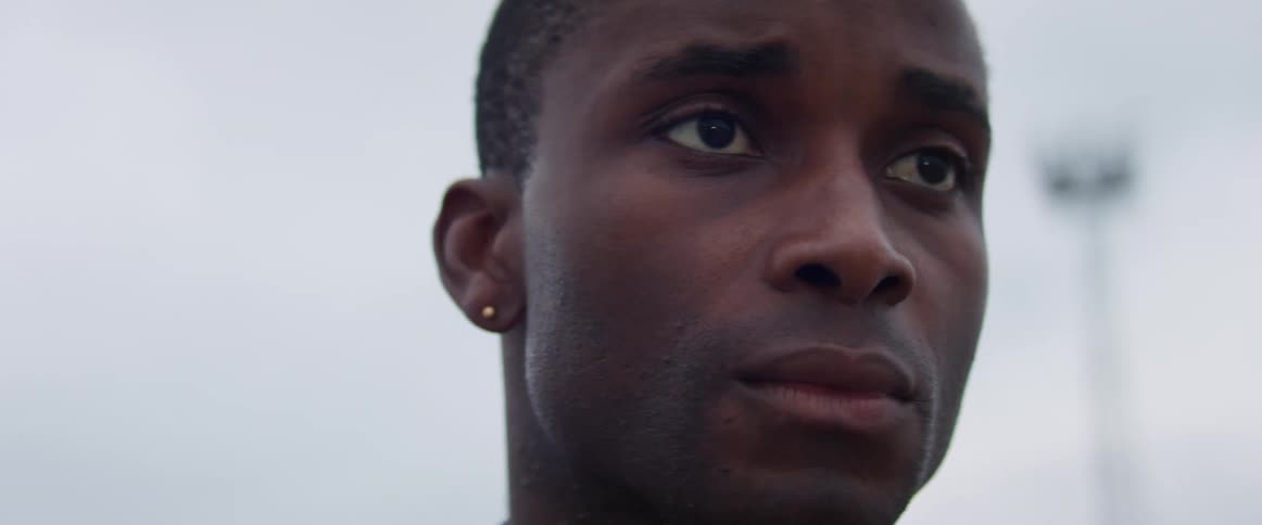 Man stands outdoors under clouds frowning