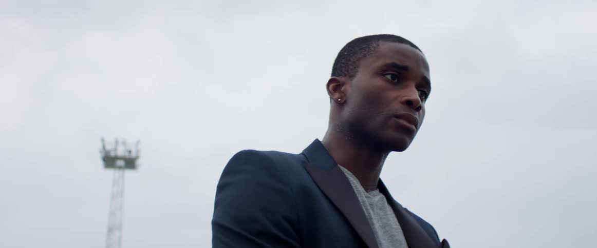 A young black man standing outside on a cloudy day