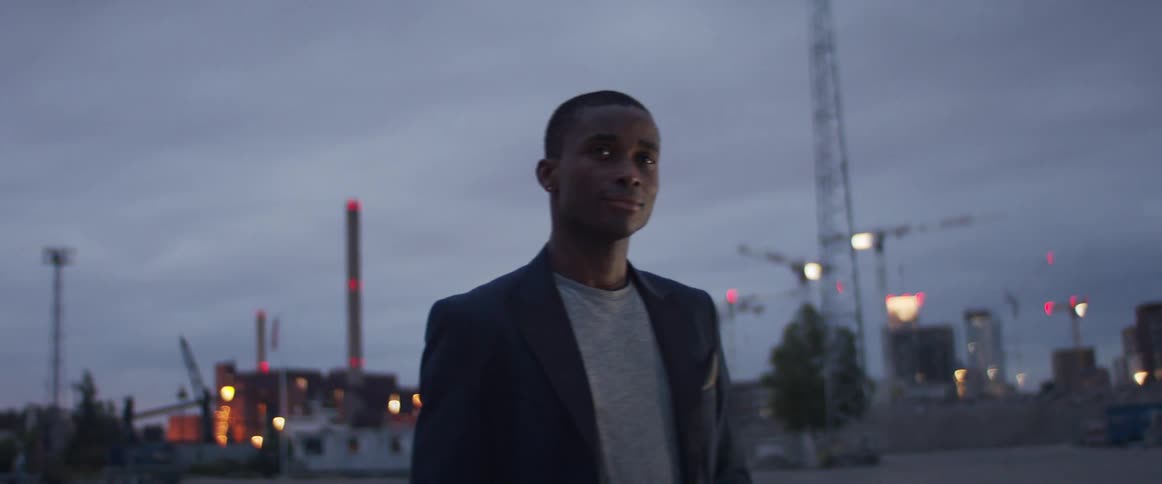 A man is walking through a city at dusk