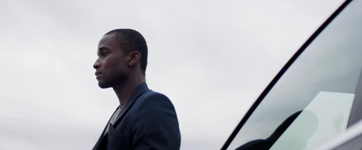 A man is standing by his car outdoors