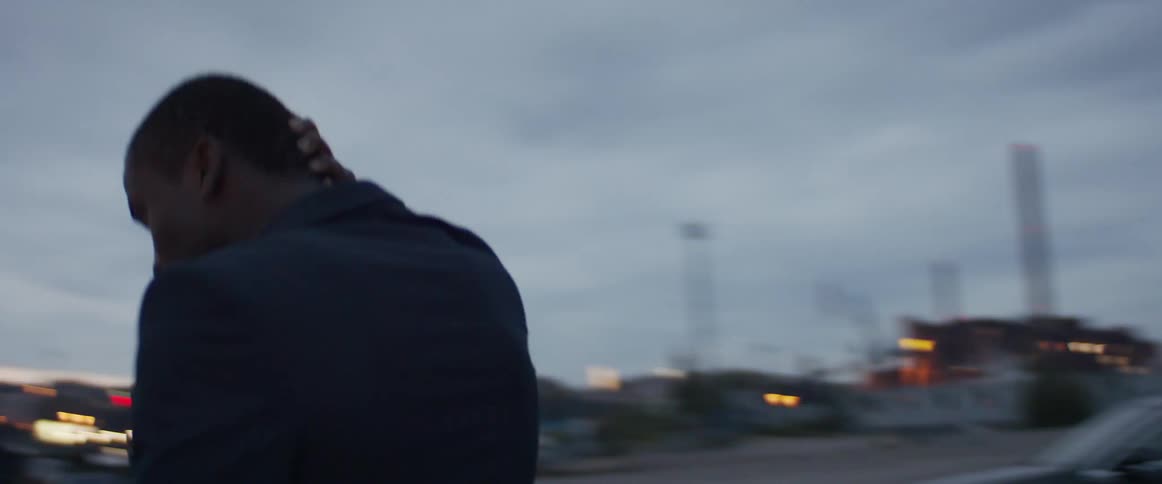 A man at a construction site rubs his head and turns in circle in a parking lot