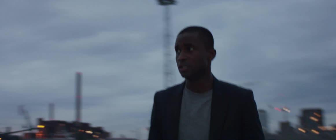 Man turns in parking lot near car with city skyline and water in area