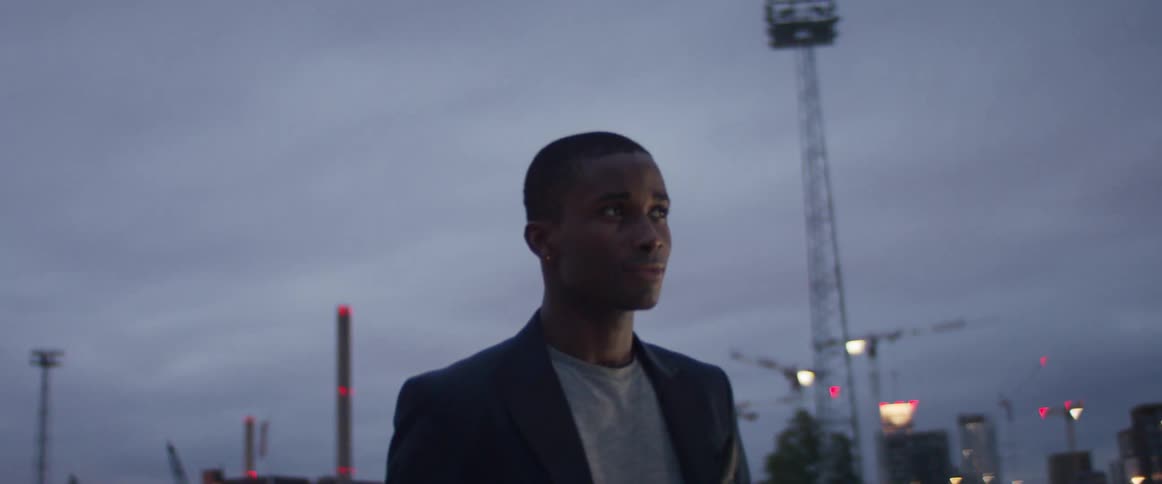 A man is standing outdoors in a city at dusk