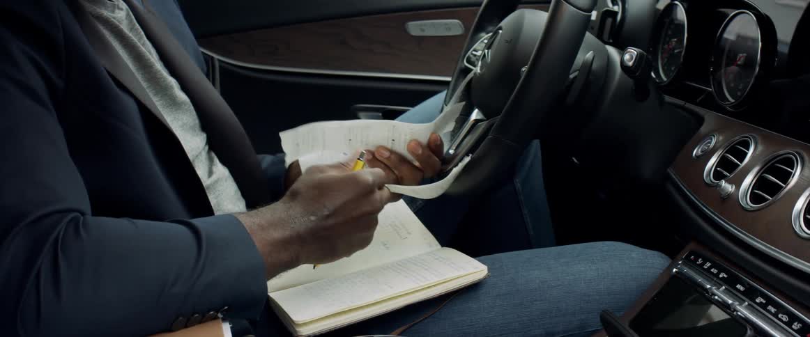 A man sits in his car and looks at receipts