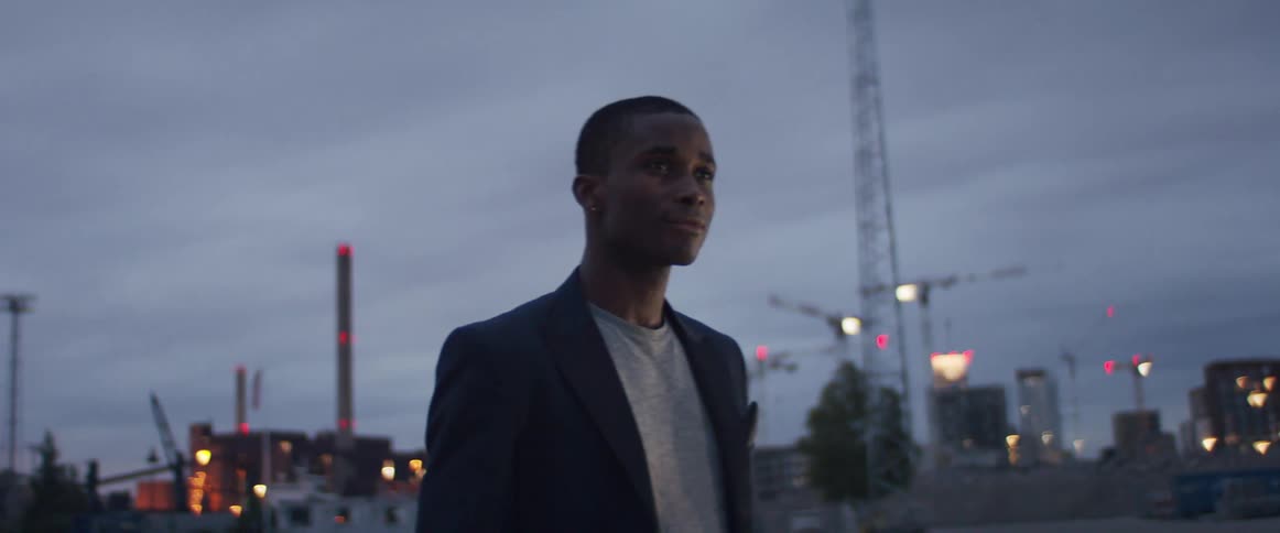 A man is walking through a city at dusk