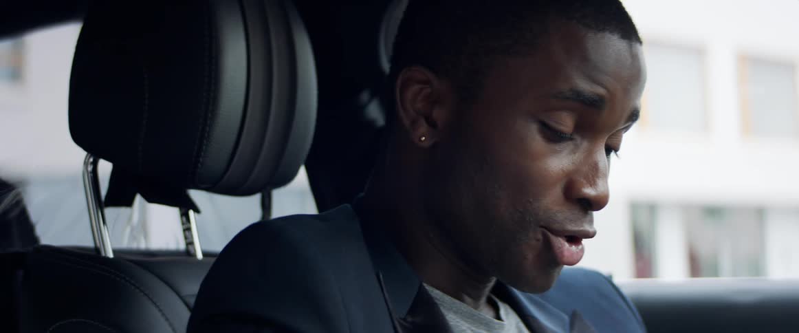 A man is sitting in his parked car during the day