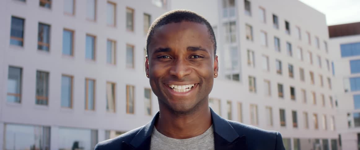 A man is smiling outside by the building