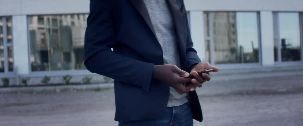 A man is using his cellphone outdoors during the day