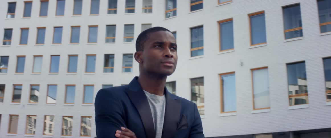 Man wearing business suit walks past skyscrapers looking up