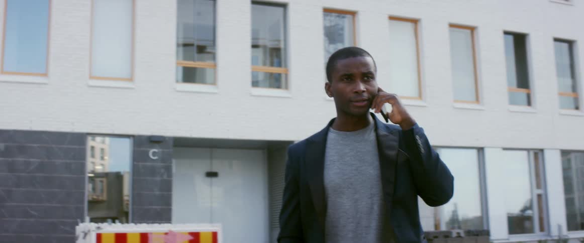 A man stands outside a large building talking on his cell phone