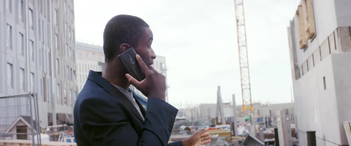 A man is talking on a cellphone while in an urban city
