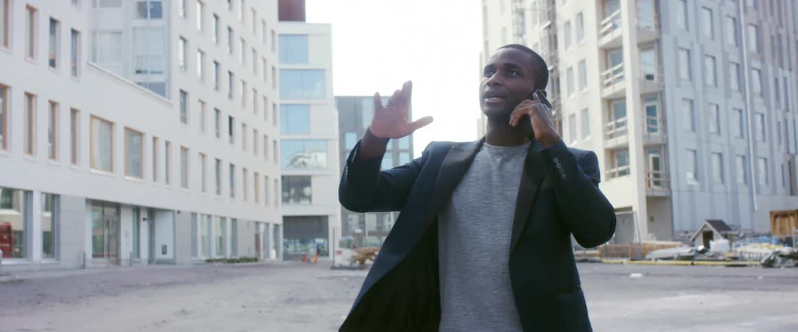 A man is walking in a city while talking on the phone