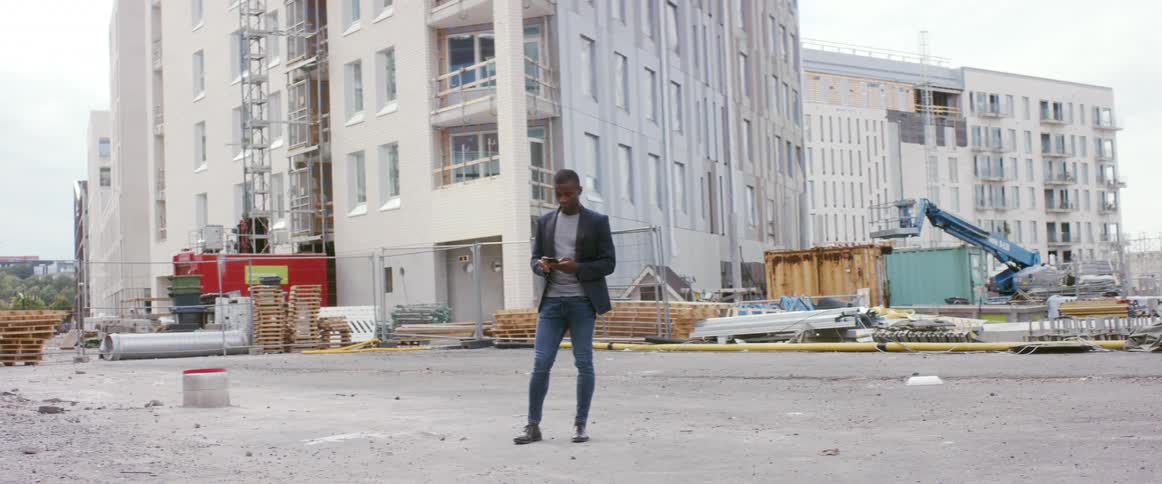 A man standing in front of a construction site uses his cell phone