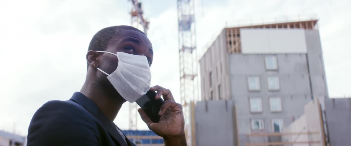 A man is talking on a cellphone while wearing a face mask
