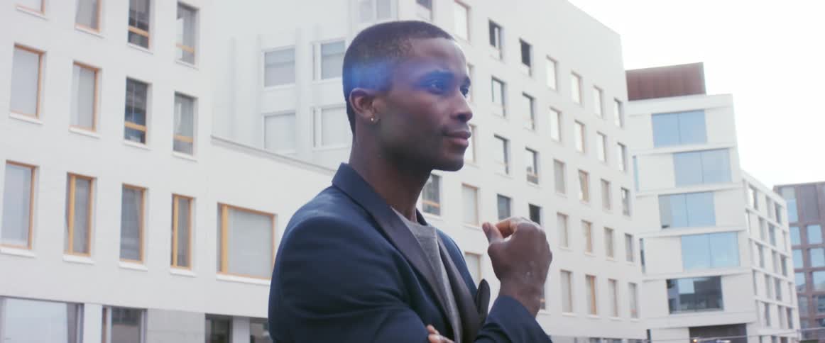 A man gazes at the buildings around him as he stands outside in a metropolis during the day