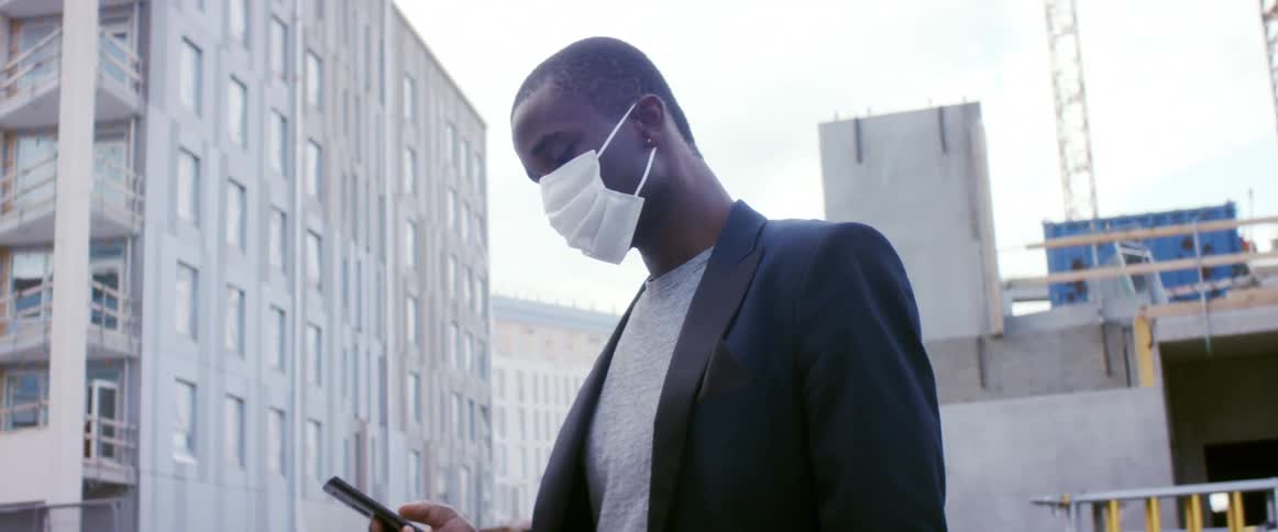 A man is standing in a city and wearing a face mask