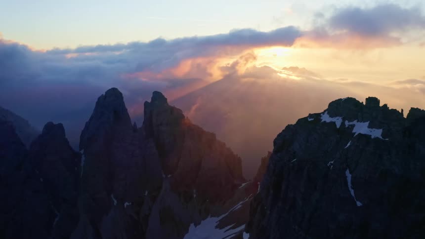 The sun setting over tall mountains with snow in winter
