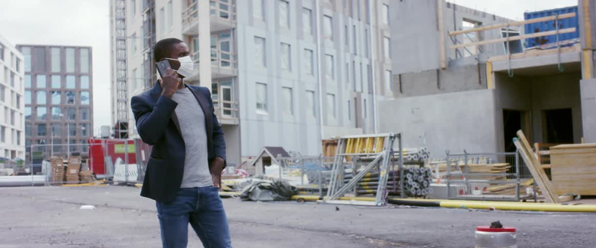 A man talks on the phone while checking out a construction site for new apartments