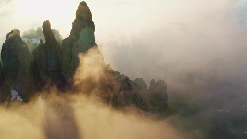 Jagged mountain peaks strewn with snow poke through the fog