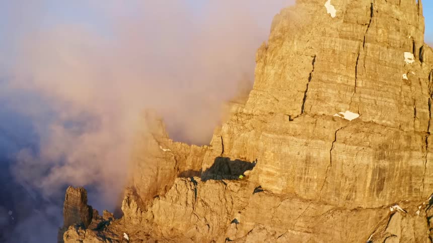 An aerial view of a rocky mountain with snow on a cloudy day