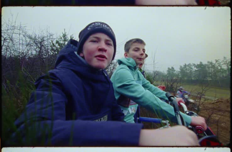Children cheer on people riding bicycles in the mud