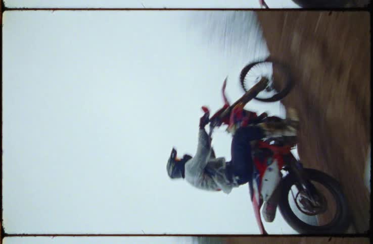 Motocross racer drive up steep dirt mount on misty day