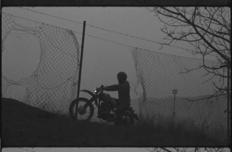 A person starts their dirt bike on the hill