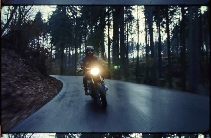 A motorcyclist rides on a quiet rural road