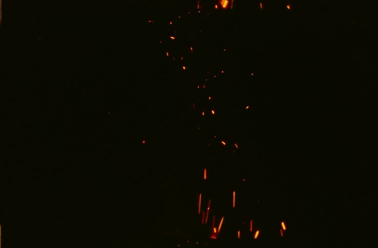 Embers floating from a campfire at night