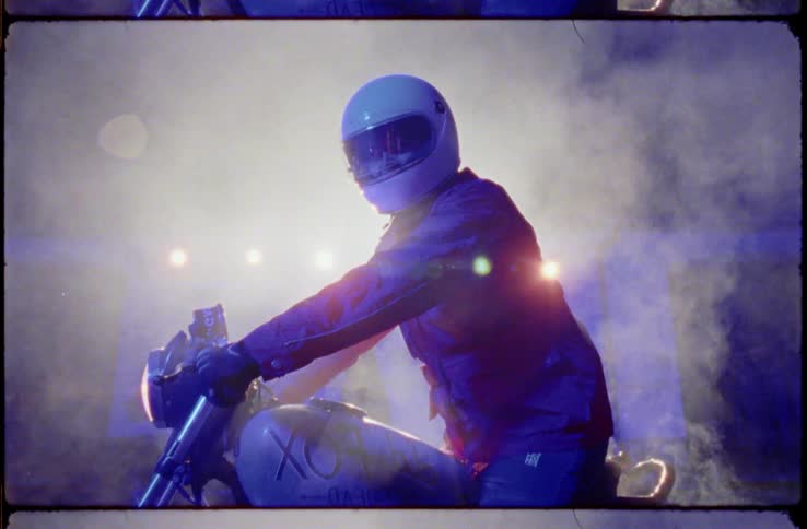 A man posing on a motorcycle engulfed in smoke