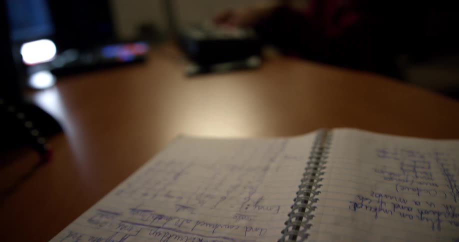 A student plays the keyboard while sitting at a desk with a noteboard nearby