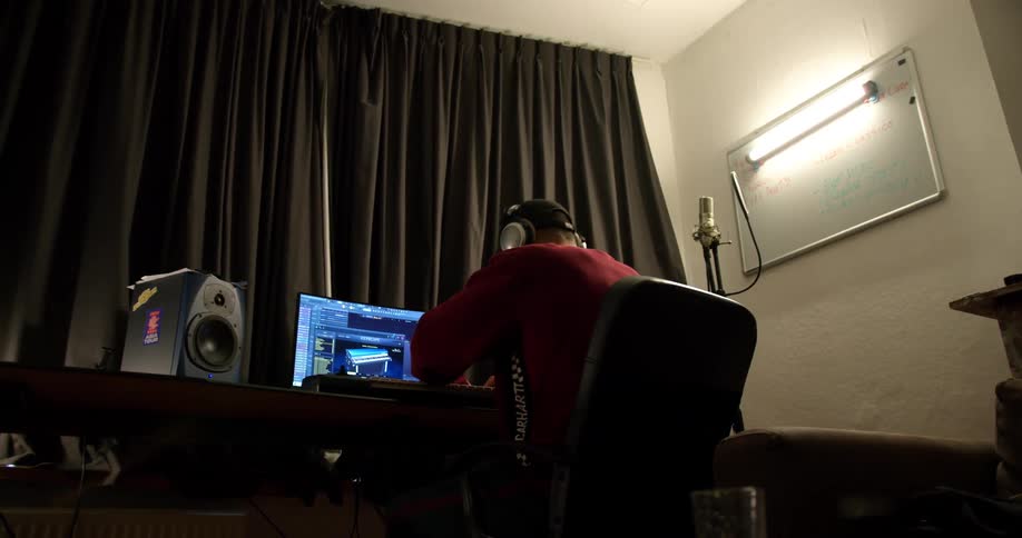 A man wearing headphones nods his head to the music while using a computer at a desk