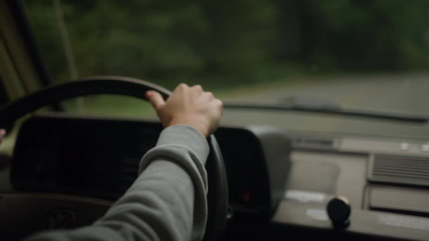 A woman is driving a car down an empty road