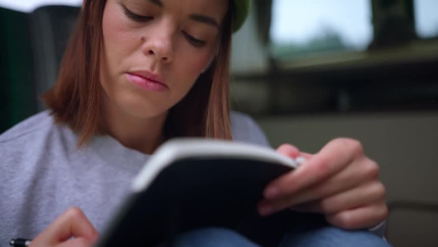 A woman is writing in a journal during the day
